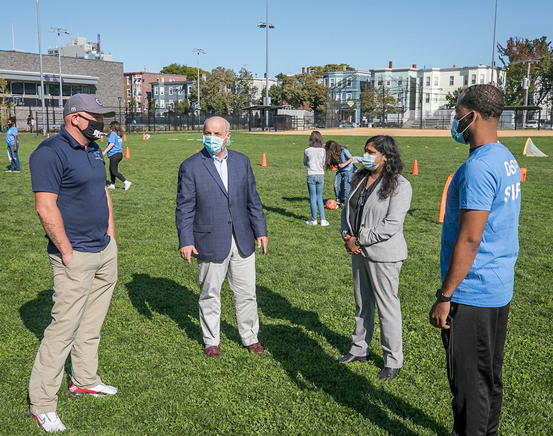 City of Cambridge Recreation Director Adam Corbeil (far left) and Donnelly Field Site Leader Larry Thompson (far right) advise Cambridge City Manager Louis A. DePasquale and Mayor Sumbul Siddiqui of the activities kids will be participating in at the Fall on the Field Kickoff. Photo by Kyle Klein.